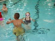 Kids swimming in pool and girl with goggles